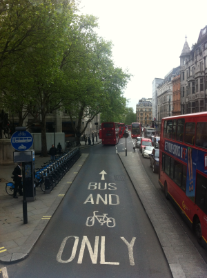 Eine Straße in London, viele der berühmten roten Doppeldeckerbusse sind sichtbar. Dazwischen drängen sich einige PKW.